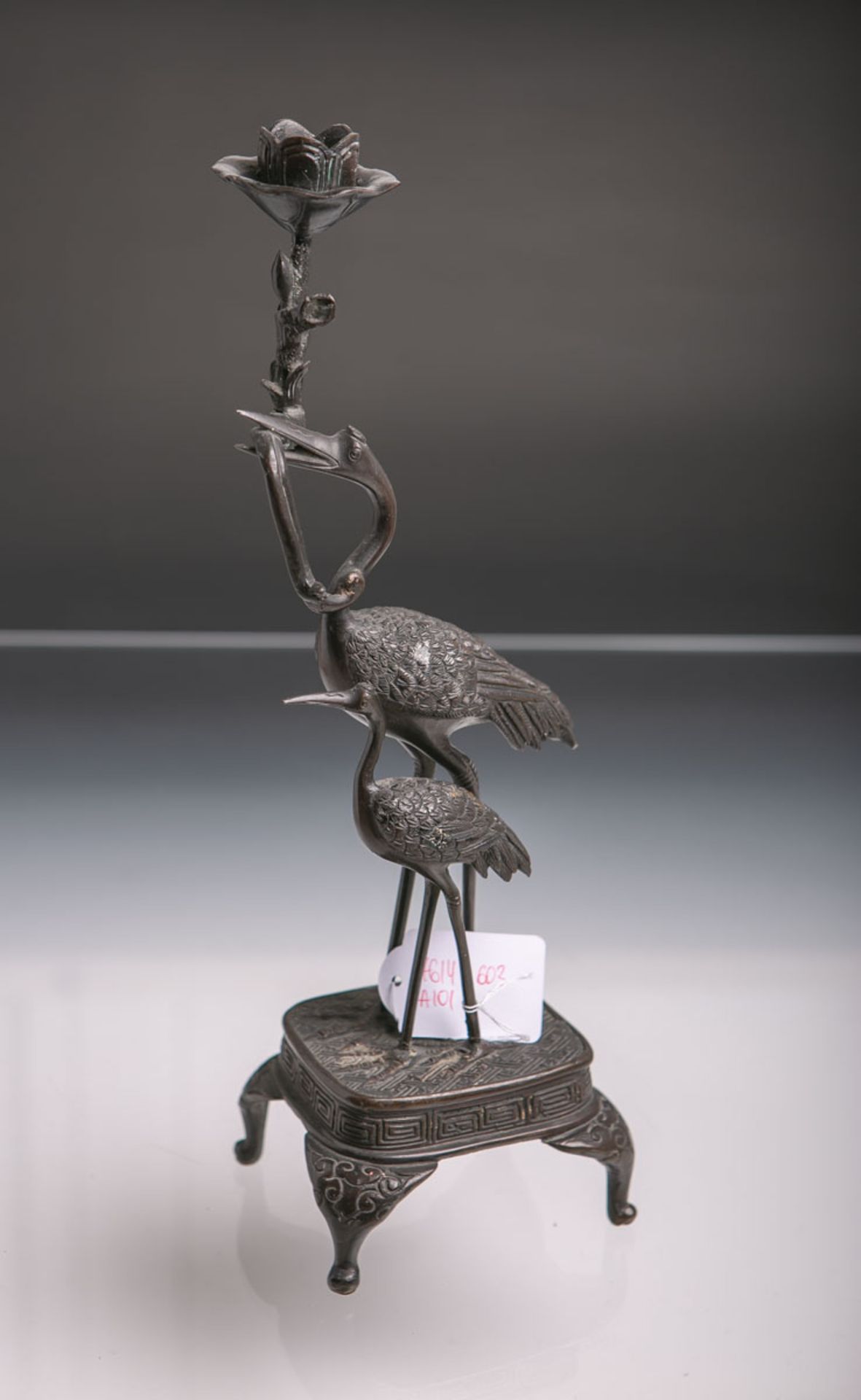 Figürliche Kerzenhalter (China, Meiji-Zeit, Ende 19. Jh.), Bronze patiniert, auf 4-füßigem Podest m.