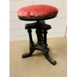 An ebonized and gilt revolving piano/music stool