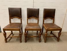 Three matching oak leather seated chairs with ring turned legs.