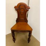 A Mahogany hall chair with shaped carved back on turned front feet.