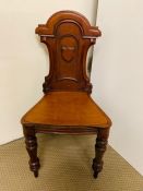 A Mahogany hall chair with shaped carved back on turned front feet.