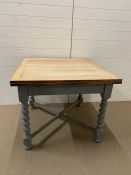 An extended dining/kitchen table with oak top and painted base