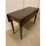 A mahogany hall table with drop sides and turned legs terminating on brass castors