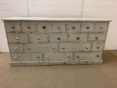 A Painted pine set of apothecary style drawers with ceramic multi coloured handles.