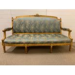 A Louis XVI style settee, foliate carved back, padded scroll down swept arms and stuffed over seat