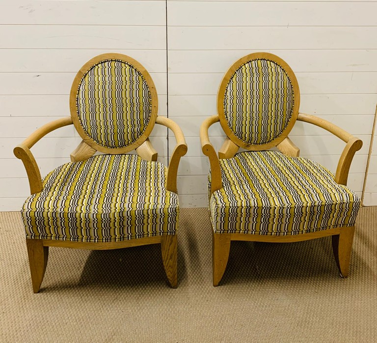 A pair of open armchairs on oak frames and circular backs (66 cm wide x 98 cm high and seat height