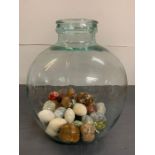 A glass carboy bottle complete with decorative stone eggs