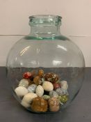 A glass carboy bottle complete with decorative stone eggs