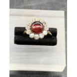 A Ruby and Diamond daisy style ring on a yellow gold setting. central ruby surrounded by twelve