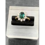 An Emerald and Diamond ring on an 18ct yellow gold setting, central emerald with ten diamonds