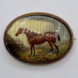 An enamel brooch of a racehorse 'Lord George' set in 18 ct gold with safety chain (Total weight 17.