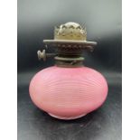 A Hinks oil lamp with a pink candy stripe glass base
