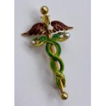 An 18ct gold enamel brooch in the style of the hypocratic oath with intertwined serpents, wings with