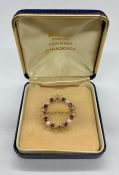 A 28mm diameter circle broochset with 4 pearls flanked by 2 rubies 2.8mm and with 4 rubies 2mm in