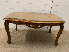 A glass topped coffee table with carved detail to legs (86cm x 55cm x 44cm)