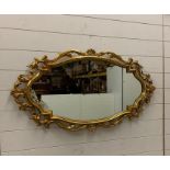 An oval gilt and scrolled mirror (H58cm W110cm)
