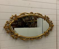 An oval gilt and scrolled mirror (H58cm W110cm)