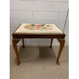 A piano stool with cabriole legs and tapestry seat