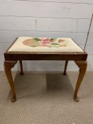 A piano stool with cabriole legs and tapestry seat