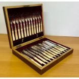 A cased set of ornate knives and forks in a wooden case.
