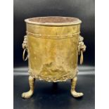 A brass plant pot on claw feet and lion head handles