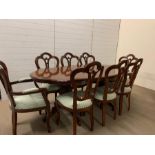A burr elm style twin pedstal dining table with six chairs and two carvers with a fold out centre