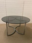 A 1960's smoked glass dining table on adjustable chrome legs (Diam 130 cm x High 72 cm)