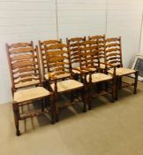 A Set of six pine ladder back rush seated chairs and two carvers