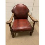 An Oak club chair with red leather upholstery and stud work