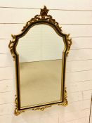 A Black and Gilt wall mirror with scrolling detail (H 106 cm x L 60 cm)