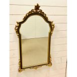 A Black and Gilt wall mirror with scrolling detail (H 106 cm x L 60 cm)