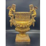 A gilt decorative modern urn with sitting angel cherubs to sides