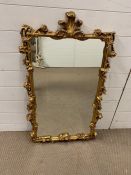 A wall mirrror in a gilt frame and fleur de lis to top (H98cm W57cm)