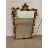 A wall mirrror in a gilt frame and fleur de lis to top (H98cm W57cm)