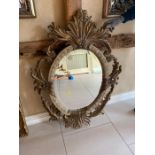 A 20th century giltwood oval mirror with floral carving