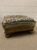 A tapestry footstool on brass bun feet