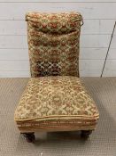 A low bedroom chair with Tapeley upholstery on turned mahogany legs on castors