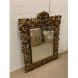 A gilt wood wall mirror framed with scrolled borders (H144cm W107cm)