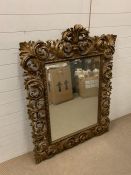 A gilt wood wall mirror framed with scrolled borders (H144cm W107cm)