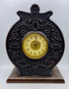 An enamel faced circular carved mantel clock.