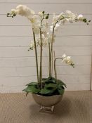 A large faux orchid in a white metal vessel