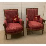 A pair of gilt armchairs in a Louis XVI style on turned tapering fluted legs