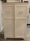 A small painted clothes cupboard or hall cupboard with heart decoration to both doors (H152cm W100cm