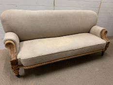 A three seater sofa with carved ends and castors (H83cm W180cm D60cm)