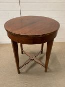 A circular mahogany table with cross stretcher