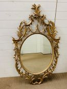A gilt frame circular mirror with carved details
