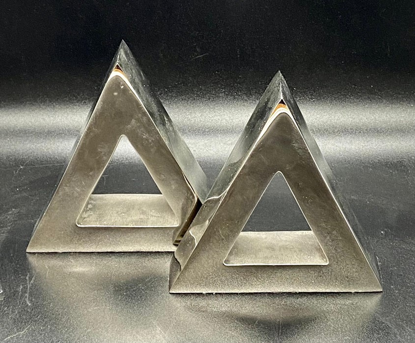 A pair of triangular white metal book ends