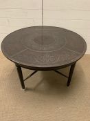 A circular low centre table or coffee table with metal top on fluted legs and a cross stretcher (