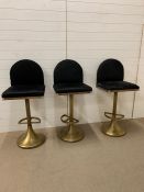 A Set of three bespoke bar stools, with a swivel action, made of brass. The fronts are upholstered