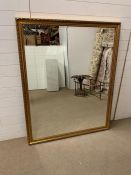 A wall mirror in a gilt frame with carved leaf boarder (146cm x 118cm)